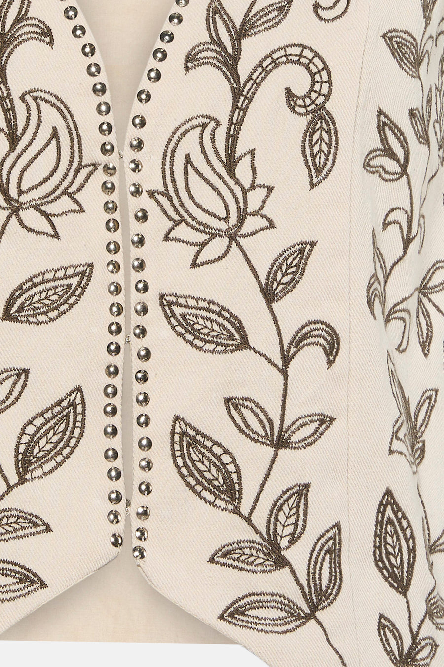 Gilet de couleur crème de VILA avec des clous argentés et une broderie florale marron foncé.