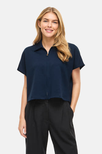 Pull bleu de VILA®, à manches courtes et avec fermeture éclair, combiné avec un pantalon noir et des talons.