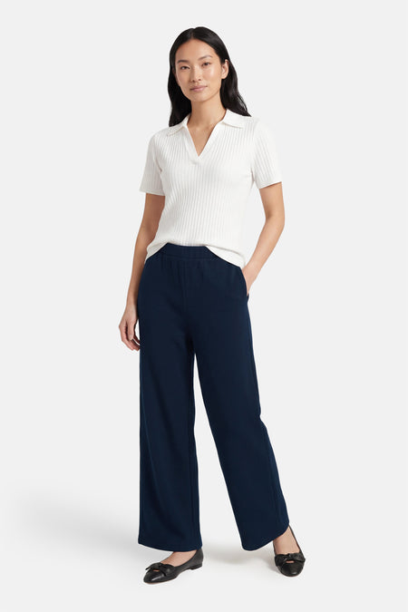 Pantalon bleu de VILA®, à jambes larges et associé à un haut blanc et des ballerines noires.