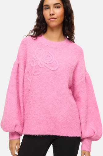 Pull rose à col rond de VILA®, avec une fleur brodée sur la poitrine et des manches ballon.