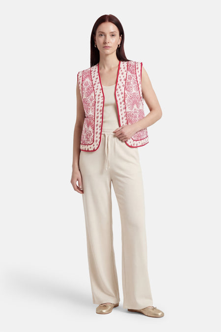 Gilet rose de VILA®, avec un motif cachemire et un passepoil rouge, combiné avec un haut et un pantalon de jogging.