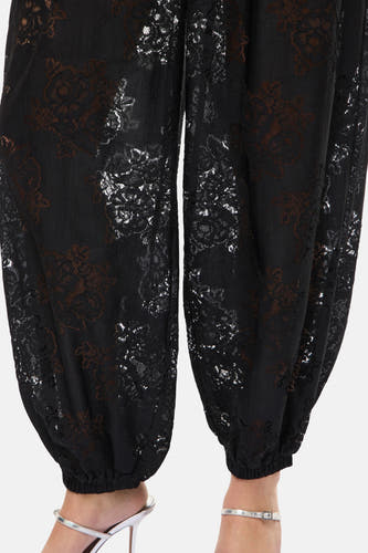 Pantalon noir de VILA, avec un motif floral et des détails de sandales argentées.