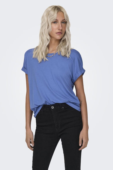 T-shirt bleu d'ONLY, avec des manches courtes et des bords de manches retroussés, porté avec un pantalon noir et des baskets blanches.