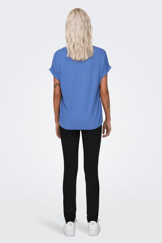 T-shirt bleu d'ONLY, avec des manches courtes et des bords de manches retroussés, porté avec un pantalon noir et des baskets blanches.