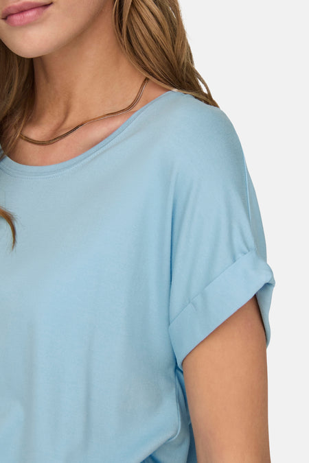 Lichtblauw T-shirt met korte, opgerolde mouwen en een gouden ketting.