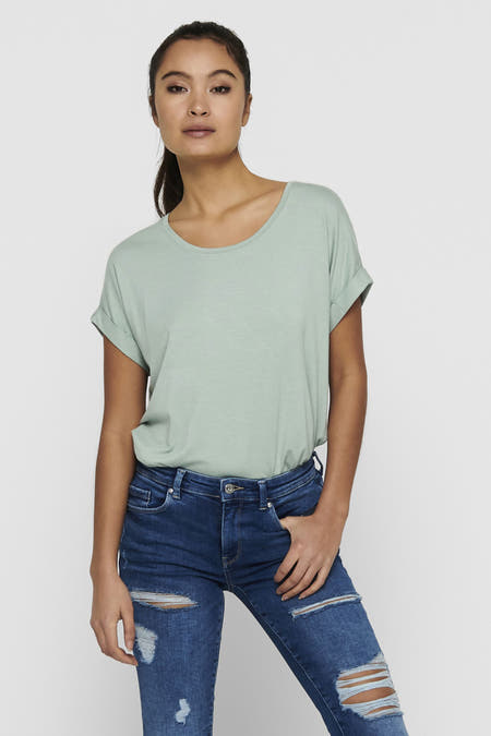 T-shirt vert de ONLY, avec des manches courtes et une couleur unie, porté avec des jeans déchirés et des baskets blanches.
