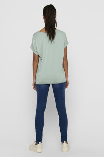 T-shirt vert de ONLY, porté avec des jeans bleus marine et des baskets crème, dos visible.