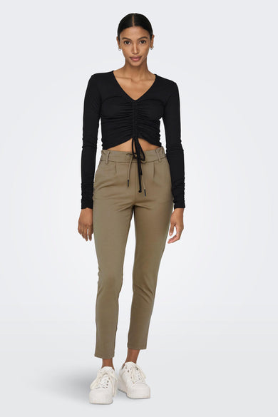 Pantalon chino brun de ONLY® avec taille à cordon, coupe ajustée et jambes courtes, porté avec un haut noir et des baskets blanches.