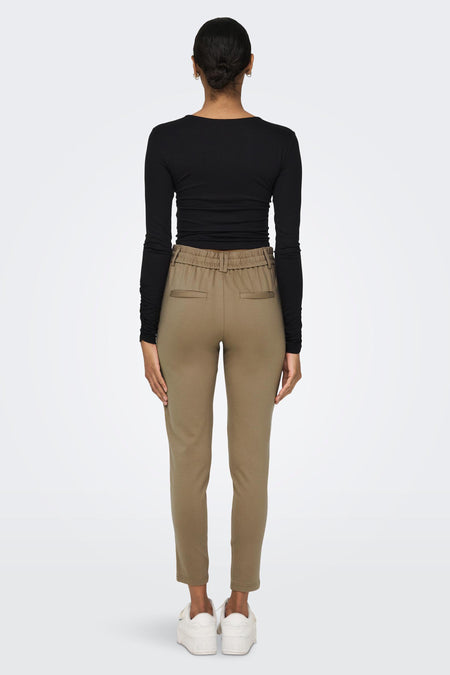 Pantalon chino bruine de ONLY® avec taille élastique, poches arrière et coupe slim, vu de dos sur un mannequin portant un haut noir et des baskets blanches