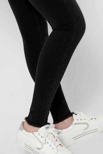 Jean skinny noir de ONLY, avec un bord côtelé et associé à des sneakers blanches.