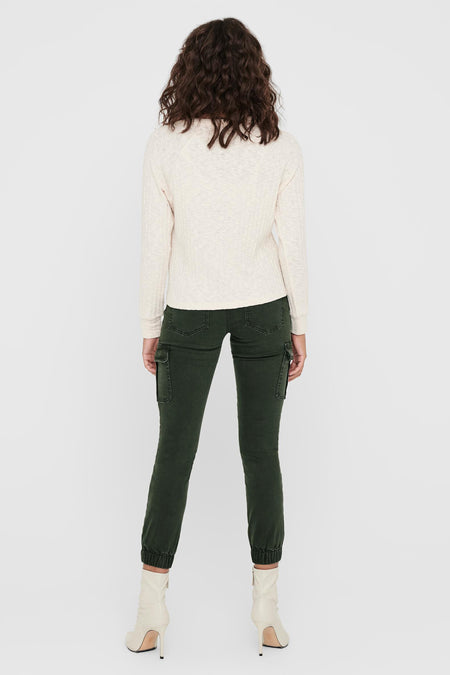 Pantalon gris de ONLY, avec des poches cargo et porté avec un pull tricoté et des bottes à talons.