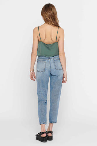 Blouse à manches courtes verte de ONLY, avec des bandes spaghetti, associée à un jean bleu et des sandales noires.