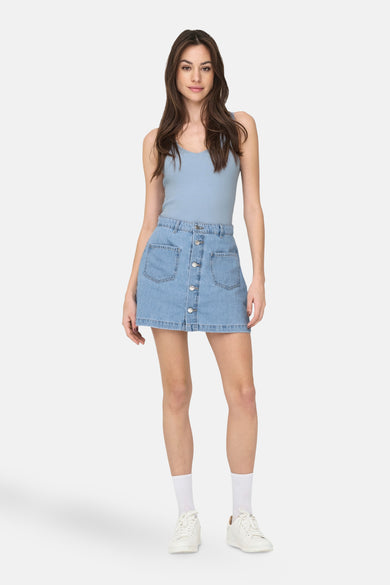 Maillot bleu de JDY, associé à une jupe en denim et des baskets blanches avec des chaussettes.