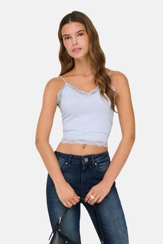 Manteau bleu ONLY, avec des détails sur les bords et porté avec un jeans foncé, des bottes noires et une sacoche.