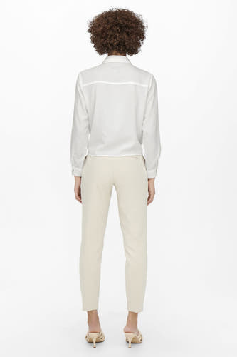 Chemisier écru à manches longues d'ONLY, avec fermeture à boutons et porté avec un pantalon beige et des talons.