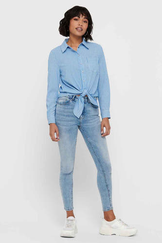 Chemise blanche à rayures à manches longues de ONLY, nouée sur le devant, avec un jean et des baskets blanches.
