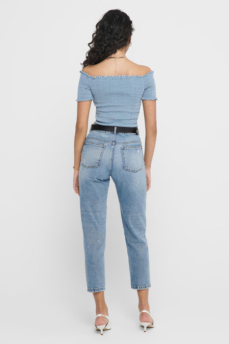 Haut en denim bleu clair avec volants de ONLY®, dos, épaules dénudées, détail froissé, le modèle porte un jean et des talons blancs
