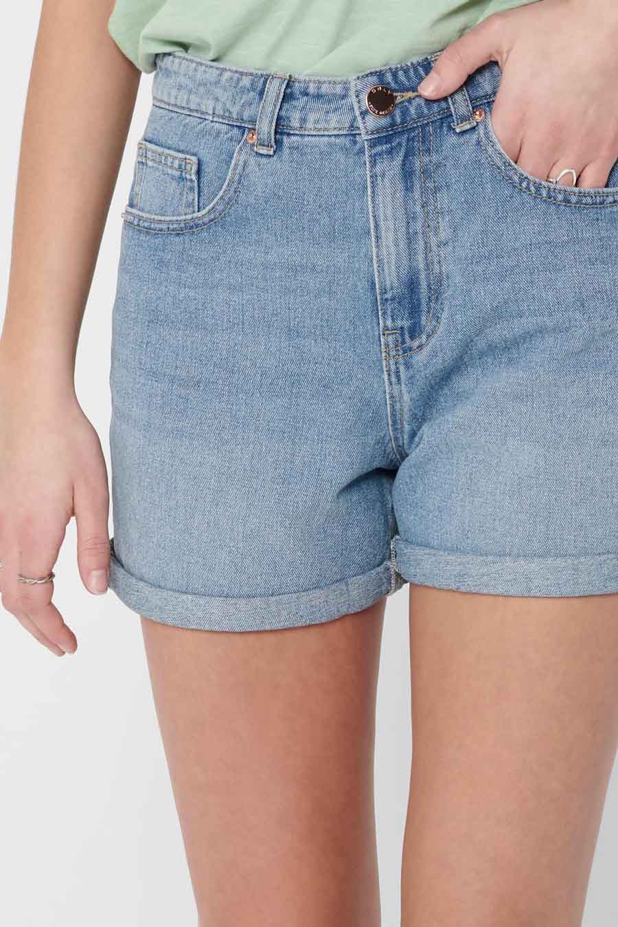 Short en denim bleu clair de ONLY, avec des poches remontées et une main dans la poche.