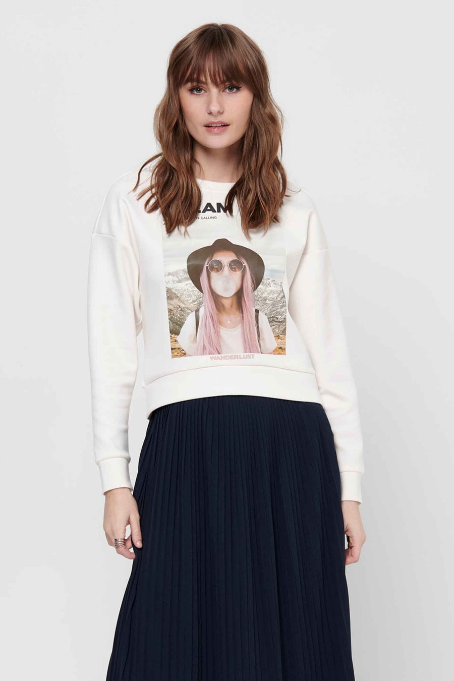 Femme avec un sweat-shirt blanc imprimé et une jupe plissée bleue.