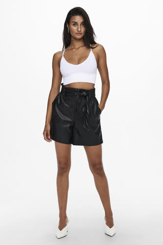 Buste blanche ONLY®, portée avec un short en cuir à taille haute et des talons blancs.