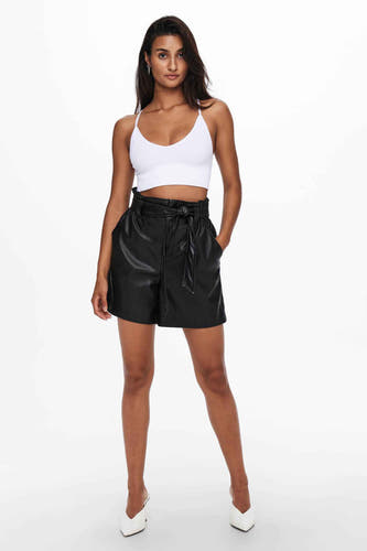 Un soutien-gorge blanc ONLY, porté avec un short en cuir noir à taille haute et des chaussures blanches.