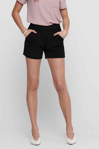 Short noir de JDY, avec des boutons et des poches, porté avec un chemisier rose et des chaussures blanches.