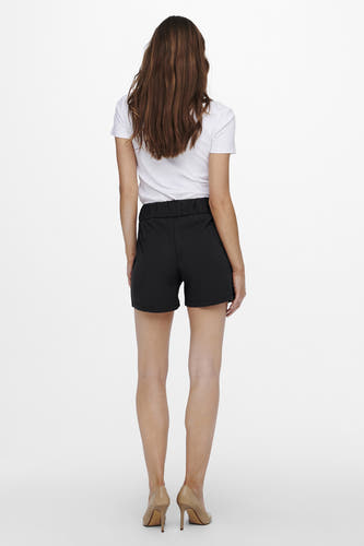 Zwarte short van JDY, met elastische tailleband, gecombineerd met een wit shirt en beige hakken, gezien van achteren.
