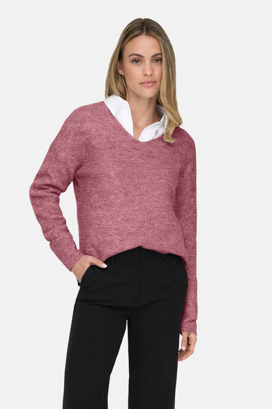 T-shirt à col V rose de ONLY, porté sur un chemisier blanc et un pantalon noir.