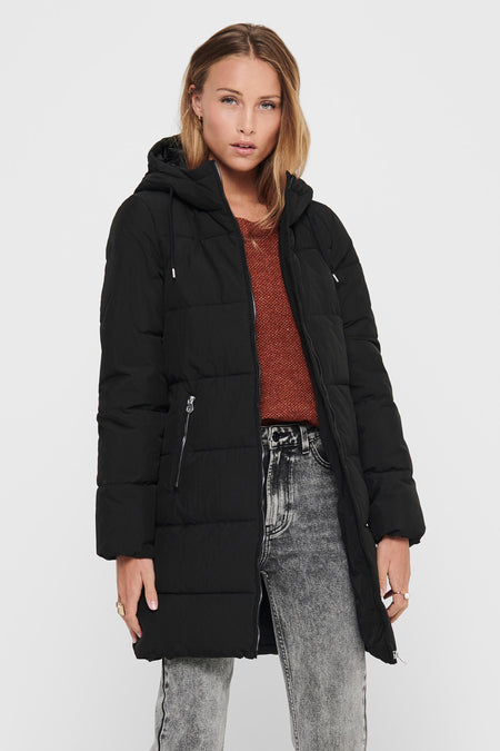 Manteau long noir ONLY®, avec capuchon, poches zippées et porté avec un pull brun, un jean gris et des bottes noires.