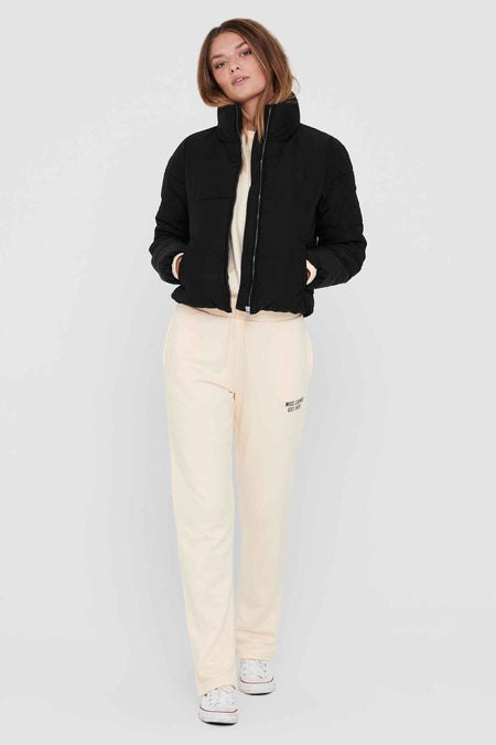 Manteau court noir ONLY, avec une fermeture éclair et des poches, combiné à un pull et un pantalon de jogging.