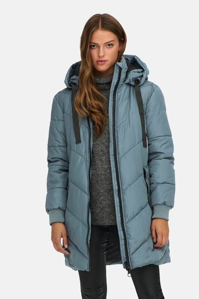 Manteau long bleu de JDY, avec capuche, détails noirs et porté sur un pull gris et un pantalon noir.
