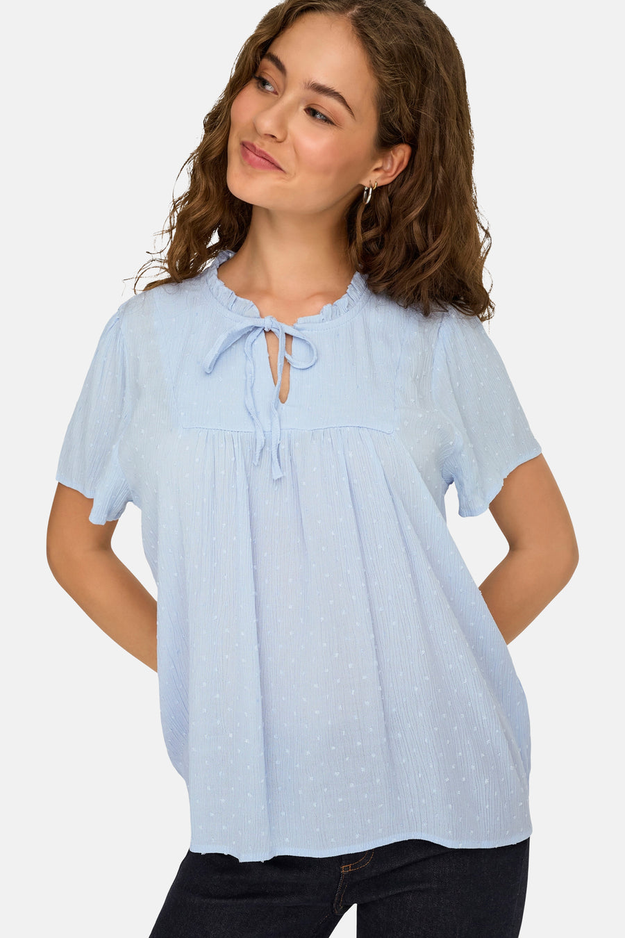 Chemisier bleu clair à manches courtes de JDY, avec tissu texturé, pois subtils, col à volants et détail de nœud.