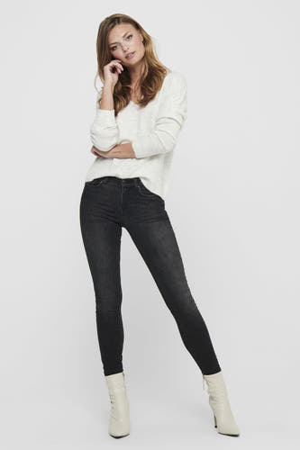 Pull-over blanc de JDY avec des manches longues, porté avec des jeans noirs et des bottes blanches.