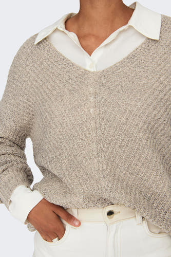 Pull marron avec col V de JDY, porté sur une chemise blanche et associé à un pantalon blanc.