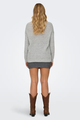 Pull-over blanc de JDY, avec des manches longues, associé à une jupe à carreaux et à des bottes de cowboy brunes.