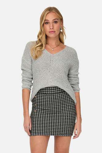Pull blanc à col V de JDY, en tissu finement tricoté, porté avec une jupe rayée noire et blanche.