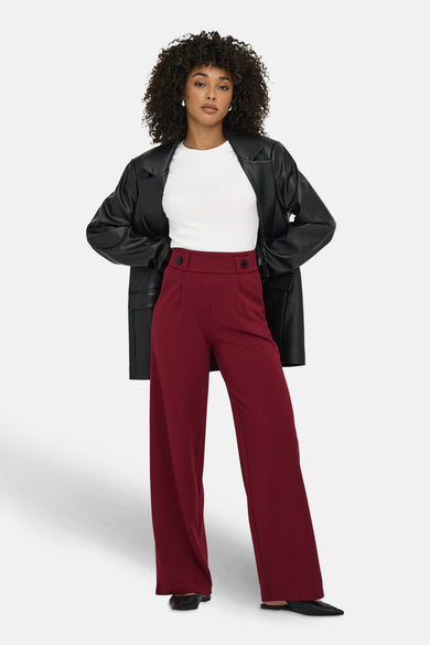 Pantalon de costume rouge JDY, associé à une chemise blanche et un manteau en cuir noir.