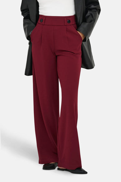 Pantalon de costume rouge JDY avec des poches larges et des détails à boutons, associé à une veste en cuir noire.
