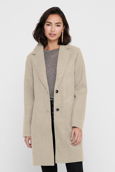 Manteau long beige ONLY, avec fermeture à boutons et col revers, porté sur une chemise brillante et un pantalon noir.