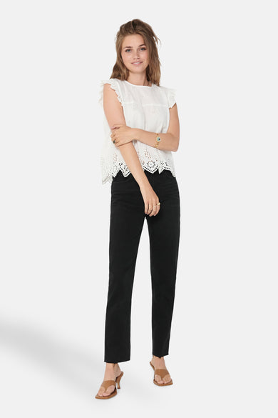 Blouse sans manches blanche ONLY, avec des détails brodés et portée avec des jeans noirs et des baskets marrons.