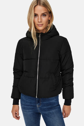 Manteau court noir de JDY, avec une fermeture éclair argentée, un capuchon et porté avec un jean bleu.