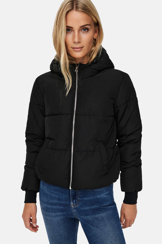 Un manteau noir en fourrure avec capuchon, porté avec des jeans bleus.