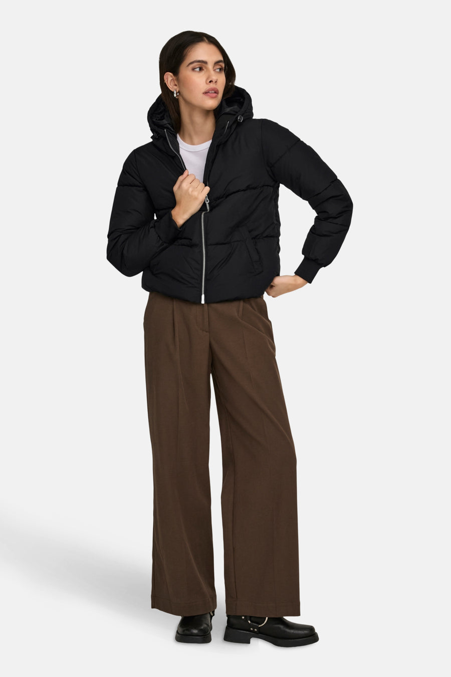 Une femme en une veste de fourrure noire et un pantalon marron.