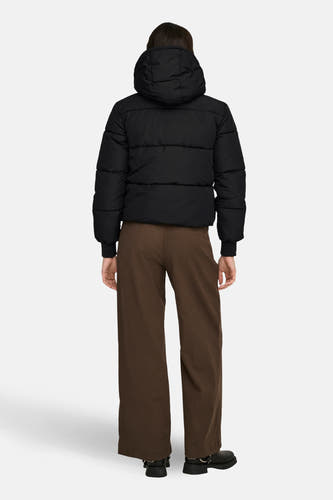 Zwarte korte jas van JDY, met een capuchon, gecombineerd met bruine pantalon en zwarte schoenen.
