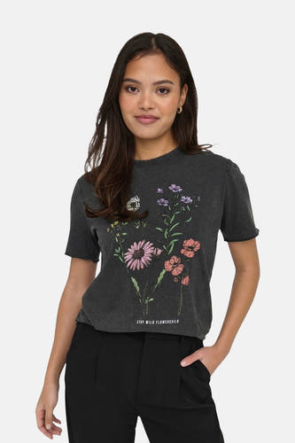 T-shirt noir à manches courtes de ONLY®, avec imprimé de fleurs et le texte "Stay Wild Flowerchild", associé à un pantalon noir.