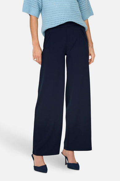 Pantalon de costume bleu JDY, avec des jambes larges et associé à une chemise bleu clair et des baskets.
