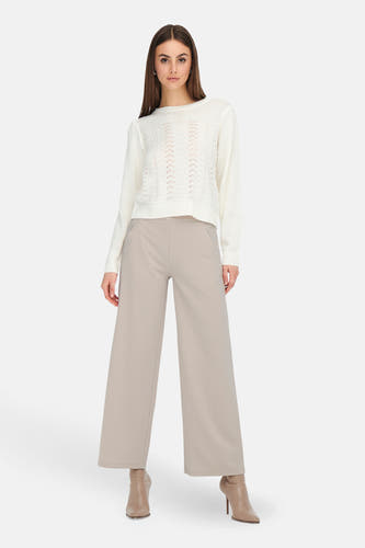 Grijze kostuumbroek van JDY, met wijde pijpen en gecombineerd met een gebreide trui en haklaarsjes.
