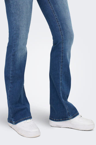 Jean flare bleu moyen d'ONLY, avec des baskets blanches.
