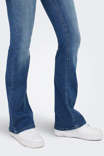 Jean en denim bleu évasé ONLY, avec des sneakers blanches.
