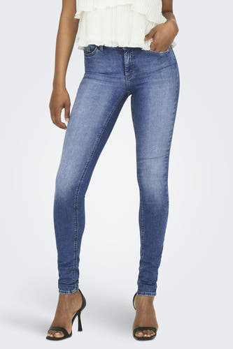 Jean skinny bleu d'ONLY, taille haute, le mannequin porte une chemise blanche et des baskets épaisses.
